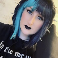 a woman wearing a black hoodie with blue hair and spikes